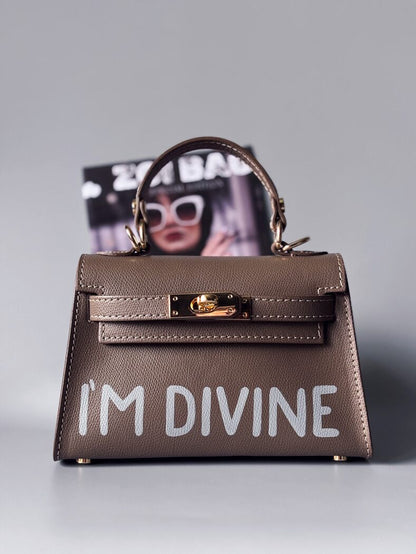 Designová luxusní tmavě béžová kabelka s ručně psaným nápisem, elegantním otočným zámkem a odnímatelným crossbody popruhem.