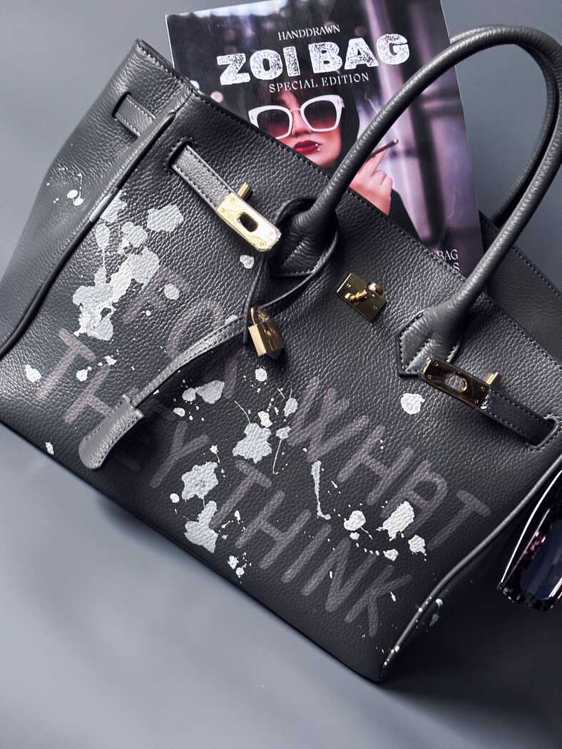 Tmavě šedá kožená kabelka Zoi Bag s ručně psaným nápisem "FCK what they think" a cákanci barvou.