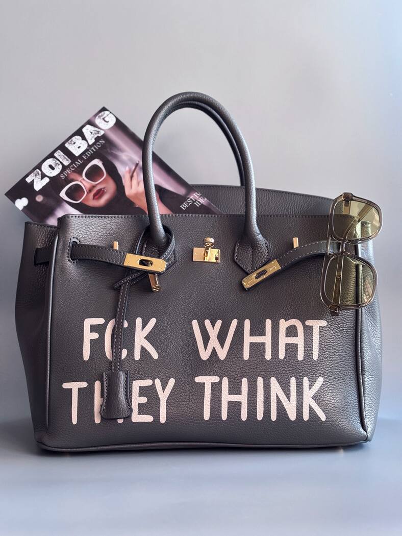 Designová luxusní kožená šedá kabelka Zoi Bag s ručně psaným nápisem. Ikonické zapínání na zámek s klíčkem.