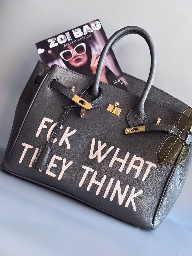 Designová luxusní kožená šedá kabelka Zoi Bag s ručně psaným nápisem. Ikonické zapínání na zámek s klíčkem.