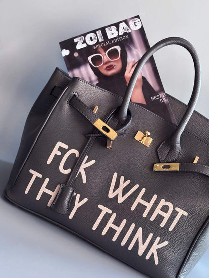 Designová luxusní kožená šedá kabelka Zoi Bag s ručně psaným nápisem. Ikonické zapínání na zámek s klíčkem.