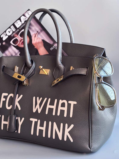 Designová luxusní kožená šedá kabelka Zoi Bag s ručně psaným nápisem. Ikonické zapínání na zámek s klíčkem.