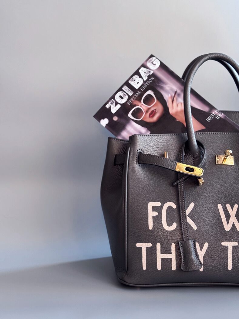 Designová luxusní kožená šedá kabelka Zoi Bag s ručně psaným nápisem. Ikonické zapínání na zámek s klíčkem. Detail.
