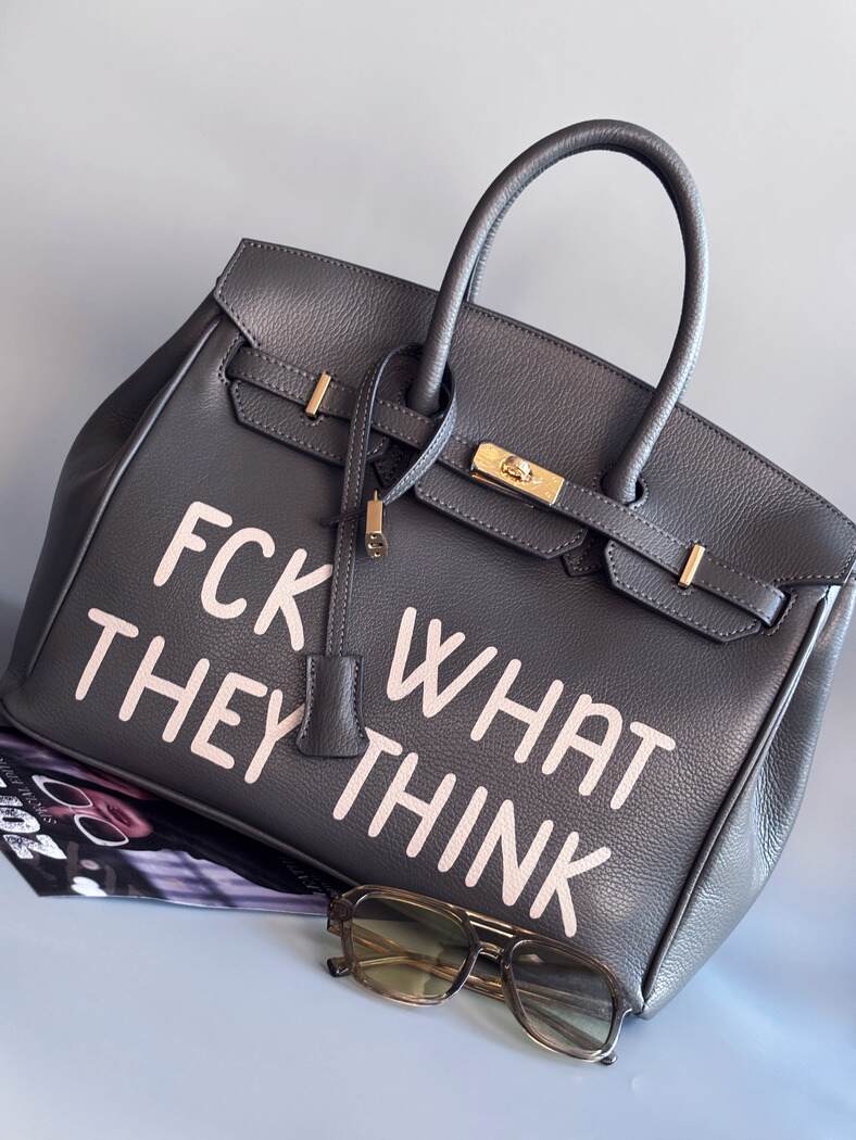 Designová luxusní kožená šedá kabelka Zoi Bag s ručně psaným nápisem. Ikonické zapínání na zámek s klíčkem. Zapnutá.