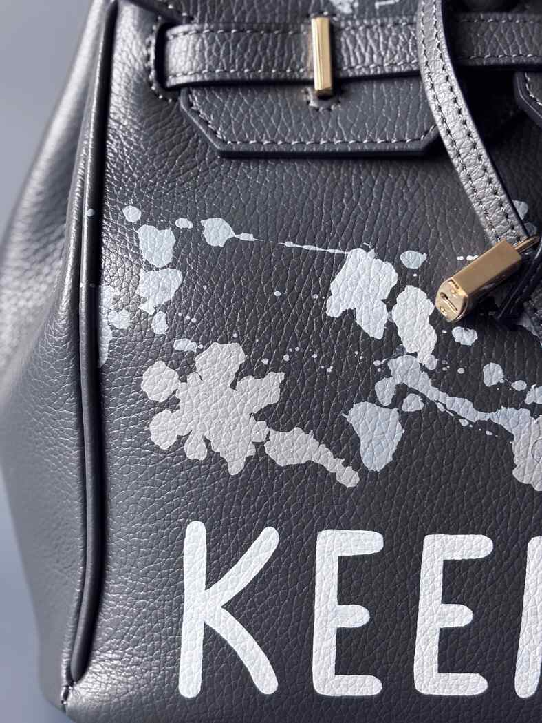 Luxusní designová kožená kabelka Zoi Bag s ručně psaným nápisem "Keep Out" a cákanci barvou. Zapínání pomocí zámku s klíčkem.