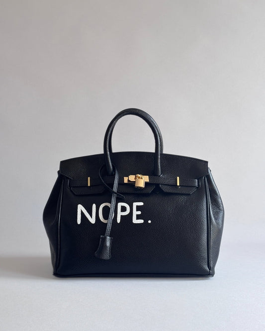 Zapnutá černá kožená kabelka Noi s motivem “Nope” z ateliéru Zoibag, pohled zepředu.