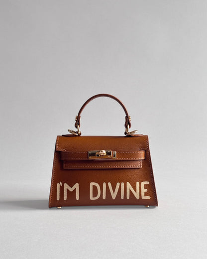 Hnědá kabelka Dao od značky Zoibag s ruční malbou “I’m divine” z italské kůže, pohled zepředu.