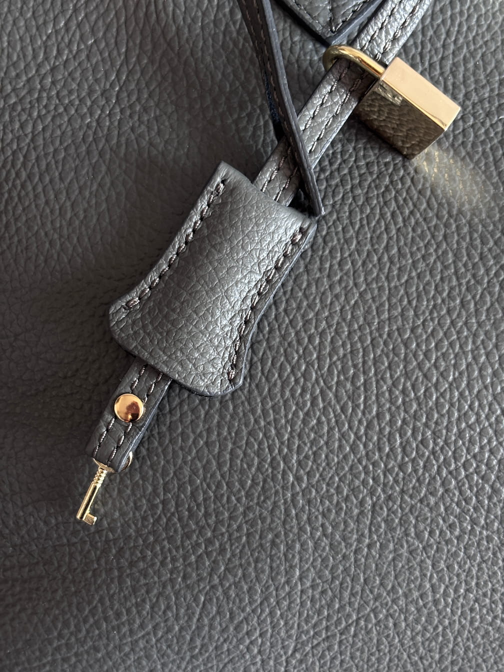 Detail zámku s klíčkem k šedé kožené kabelce Dea od značky Zoibag.